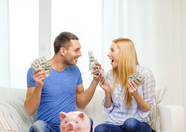 Couple with money and piggybank ot table at home - Фото, зображення