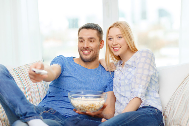 Smiling couple with popcorn watching movie at home - 写真・画像