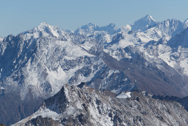 Snowy peaks of the Caucasus mountain range against a blue sky. - Foto, afbeelding