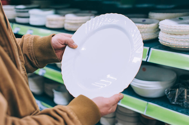 The guy in the supermarket is holding plates for food - Foto, Imagem