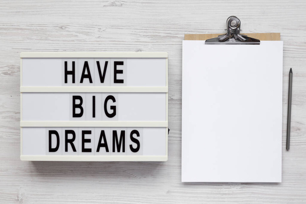 'Have Big Dreams' on a lightbox, clipboard with blank sheet of paper on a white wooden background, top view. Flat lay, overhead, from above.  - Photo, Image