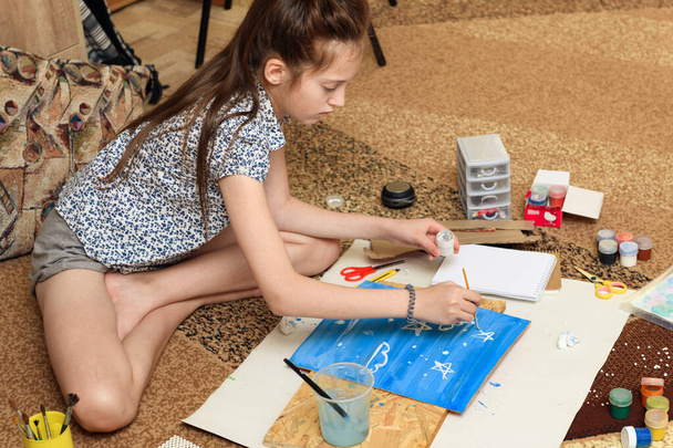 menina desenha em casa, criação artística, faz arte criativa a partir de papel, tintas e pincéis - Foto, Imagem