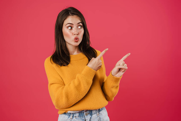 Image of shocked beautiful girl pointing fingers aside isolated over pink background - Fotografie, Obrázek