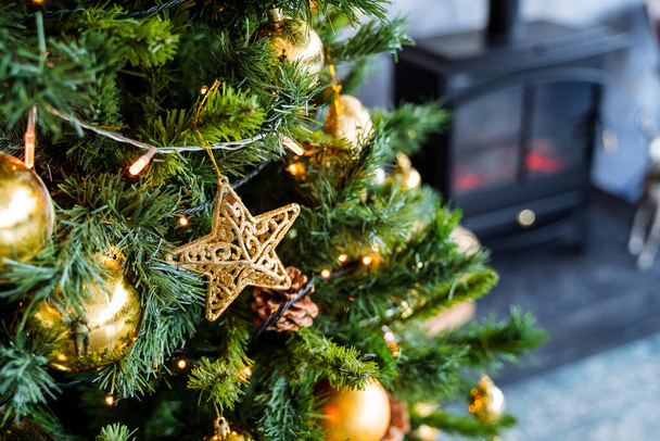 Golden star on the Christmas tree, Christmas tree decoration with Golden balls garland, green spruce in the interior of the apartment, preparation for the Christmas holiday - Photo, image