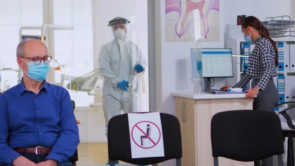 Врачи-стоматологи в защитном костюме проводят рентген зубов в приемной - Кадры, видео