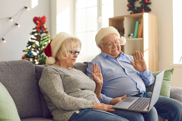 Senior couple using laptop makes a video call to congratulate their family on Christmas. - Фото, изображение