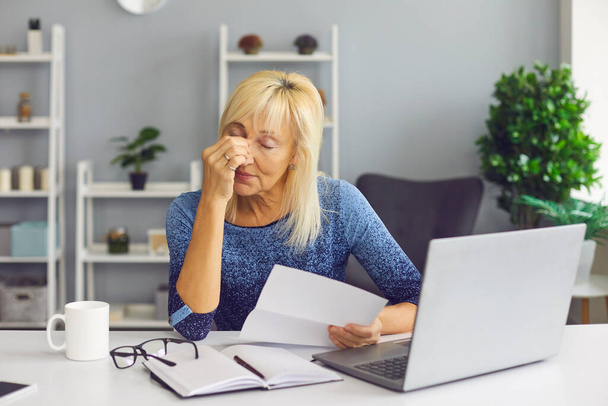 Tired senior woman receiving bankruptcy notification or rejection letter and crying - Photo, Image