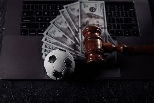Футбольный мяч и деревянный молоток на клавиатуре ноутбука. Коррупция в спорте или пари - Фото, изображение
