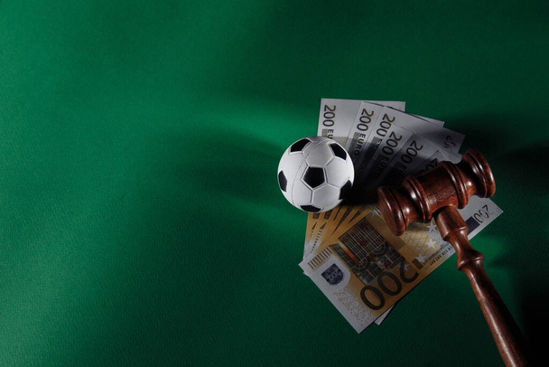 Soccer ball and judge gavel on green background. Corruption in sports or betting concept - Photo, Image