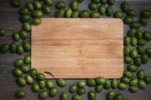 Zelené čerstvé olivy na dřevěném pozadí. Ekologický produkt. - Fotografie, Obrázek
