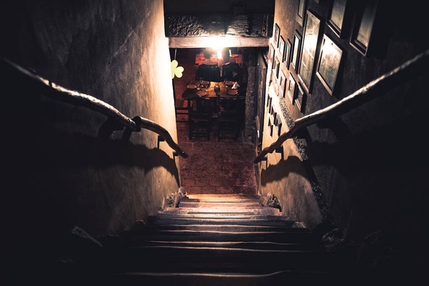 Punto di vista drammatico di scale spaventose da capovolto in oscurità di interno di pub vecchio - Foto, immagini