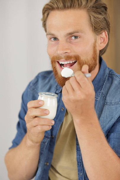 a young man eating a yogurt - Foto, Imagen