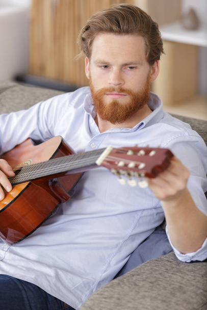 young man tuning his guitar - Photo, Image