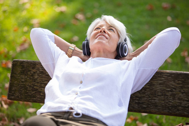 happy senior woman listening music with headphones and smartphone - Фото, изображение