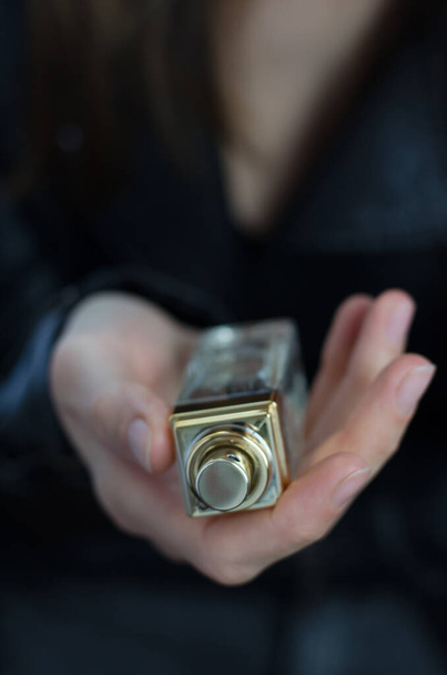Botella de perfume en la mano de la mujer joven de cerca - Foto, Imagen
