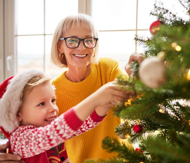 Mutlu aile babaannesi ve neşeli torun Noel ağacını holida için süsleyin. - Fotoğraf, Görsel