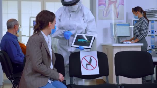 Стоматолог в покрытии с помощью планшета объяснение стоматологического рентгена - Кадры, видео