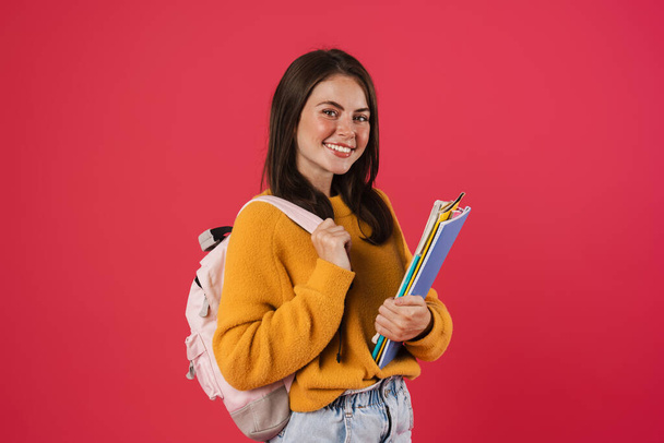Obraz szczęśliwy piękny student dziewczyna pozowanie z zeszyty ćwiczeń izolowane na różowym tle - Zdjęcie, obraz