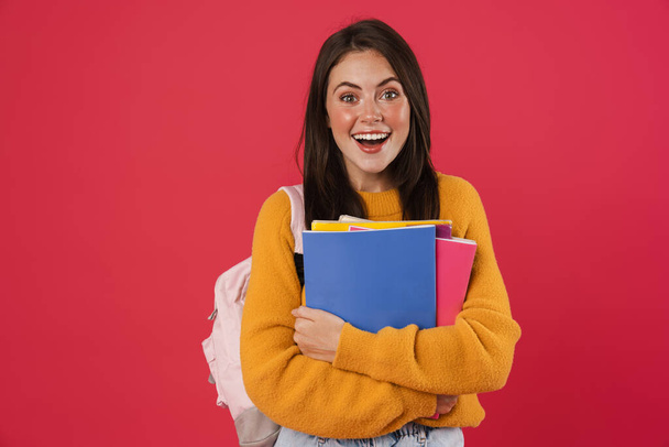 Image of excited beautiful student girl posing with exercise books isolated over pink background - Фото, зображення