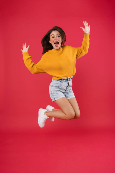 Full length portrait of a cheerful woman jumping isolated on a pink background - Photo, Image