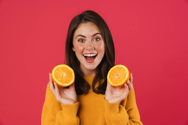 Image of excited caucasian girl posing with orange isolated over pink background - Foto, Imagem