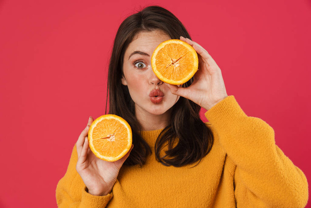 Image of surprised caucasian girl posing with orange isolated over pink background - Fotó, kép
