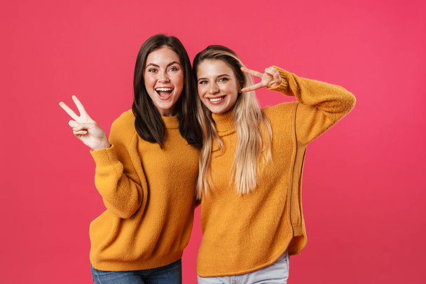Image of joyful beautiful women hugging and gesturing peace sign isolated over pink background - Fotoğraf, Görsel