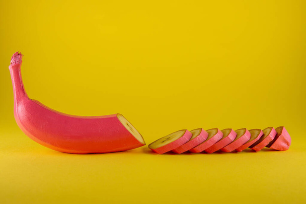 Pink banana on yellow background. Half sliced. Minimal food concept - Photo, image