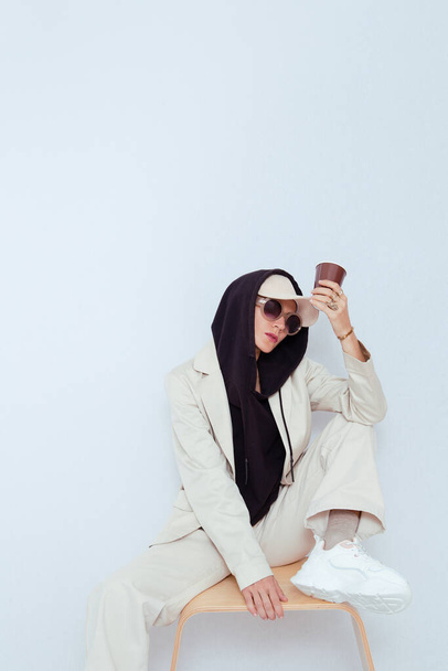 Model in white studio. Trendy beige casual outfit with black hoodie accent.  Cap, sunglasses, Denim Suit Jacket and Pants. Street Urban Style. Fall winter season.  Fashion lookbook concept - Foto, imagen