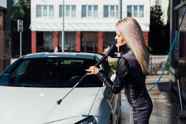 Beautiful blonde woman washes white car at car wash - Foto, immagini