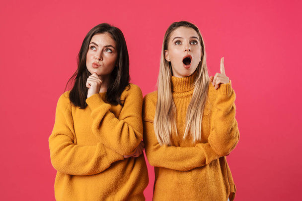 Image of nice beautiful women thinking and pointing finger upward isolated over pink background - Fotoğraf, Görsel