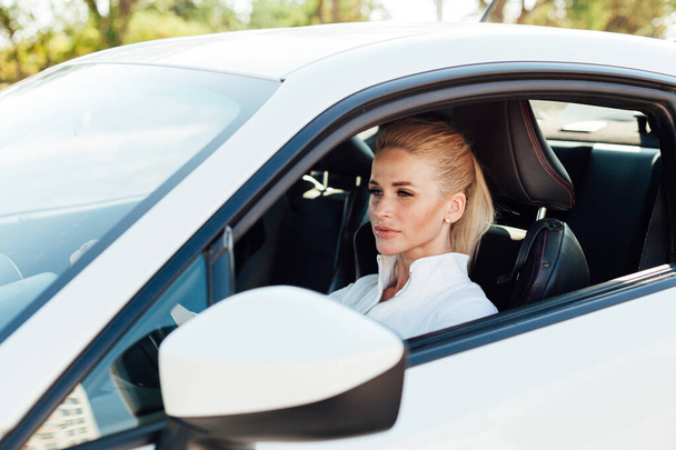 Красива блондинка на дорозі за кермом білої машини
 - Фото, зображення