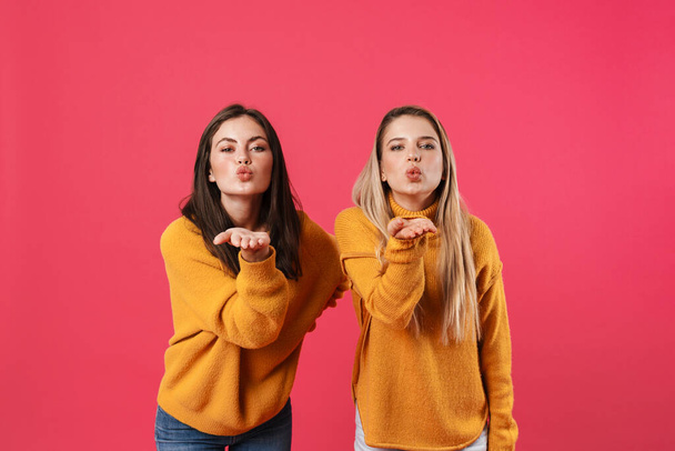 Image of caucasian beautiful women blowing air kisses at camera isolated over pink background - Fotoğraf, Görsel