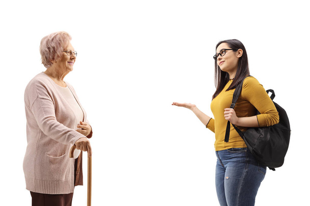 Elderly woman with a cane and a female student gesturing with hand isolated on white background - Fotó, kép