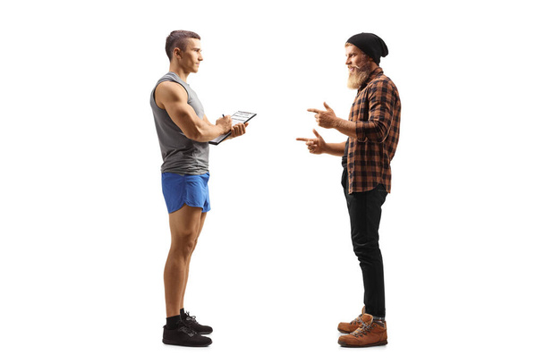 Full length profile shot of a hipster talking to a fitness trainer isolated on white background - Photo, image