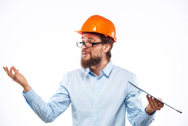 Wesoły człowiek w pomarańczowym twardym kapeluszu dokumenty budowlane usługi profesjonalistów - Zdjęcie, obraz