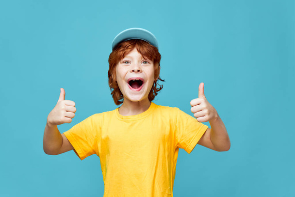 Joyeux garçon aux cheveux roux avec des gestes de bouche ouverte avec ses mains émotions vue recadrée T-shirt jaune  - Photo, image