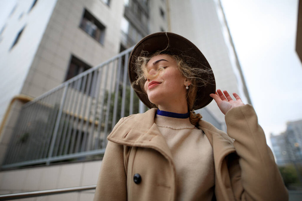 Stylish woman in hat posing for camera against the background of the city - Photo, image