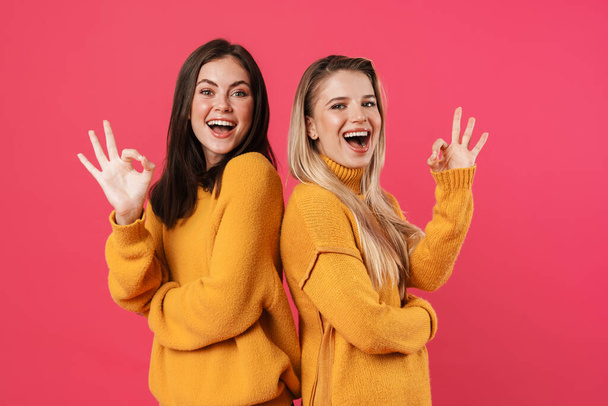 Image of smiling beautiful women showing ok sign isolated over pink background - 写真・画像