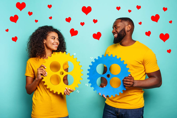 Couple with gears in hand over light blue background. Concept of meeting and love - Foto, imagen