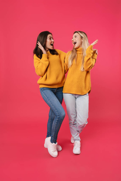 Image of excited caucasian women hugging with throwing up hands isolated over pink background - Fotoğraf, Görsel