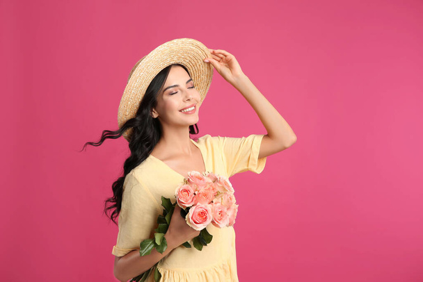 Portrait of smiling woman with beautiful bouquet on pink background - Zdjęcie, obraz