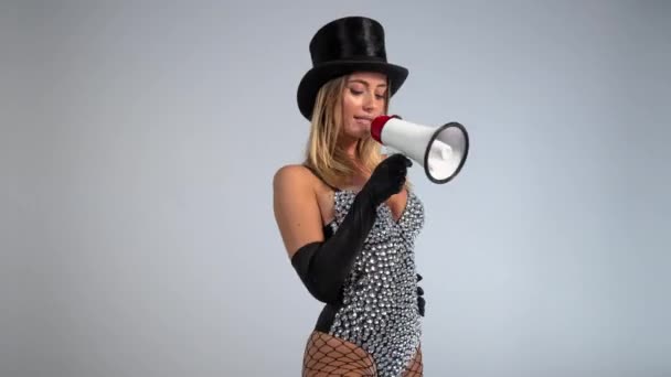 Mujer joven con sombrero de copa negro y medias de red usando megáfono - Metraje, vídeo