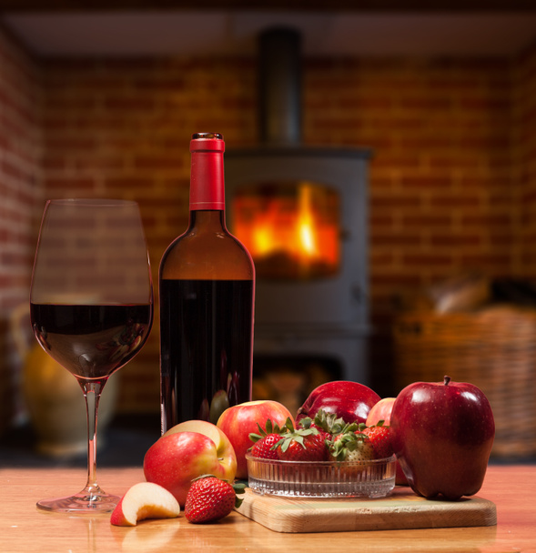 κόκκινο κρασί και φρούτα μπροστά από φωτιά - Φωτογραφία, εικόνα