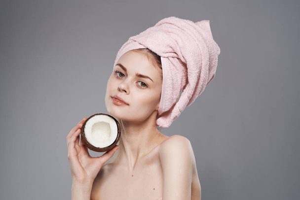 mulher com toalha na cabeça ombros nus coco na mão corte vista fundo cinza - Foto, Imagem