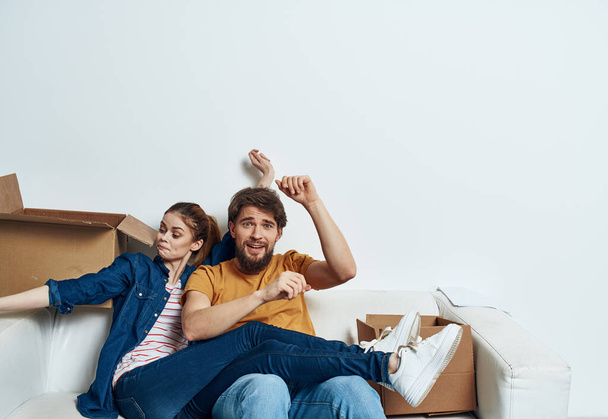 alegre hombre y mujer en el sofá moviendo cajas de cartón interior - Foto, Imagen