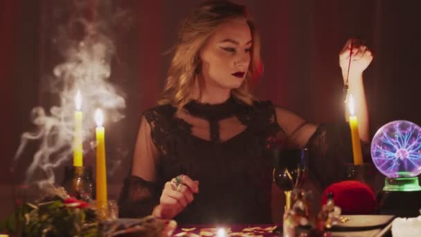 Žena věštkyně drží magické kyvadlo nad svíčkou - Záběry, video