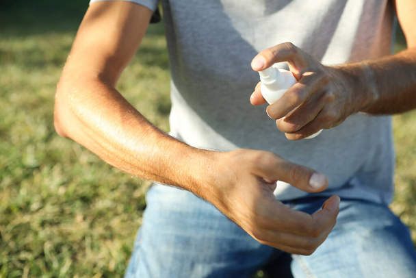 Man applying insect repellent onto arm outdoors, closeup - Fotoğraf, Görsel