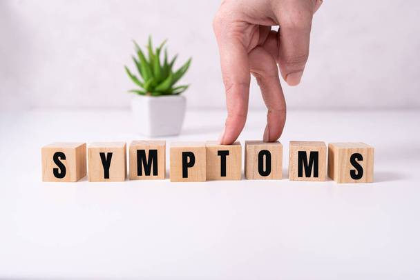 SYMPTOMS text word on wooden cubes on white background. - Фото, изображение