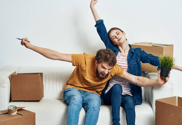 Cheerful young couple in the room on the couch with boxes moving - Photo, Image